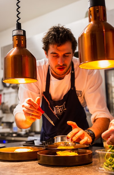 A chef's portrait, smiling slightly, against a dark backdrop